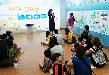 교욱이벤트 행사장에서 행사중인 강의실 모습 부모와 아이들이 바닥에 앉아서 강사의 강연을 듣고 있다.